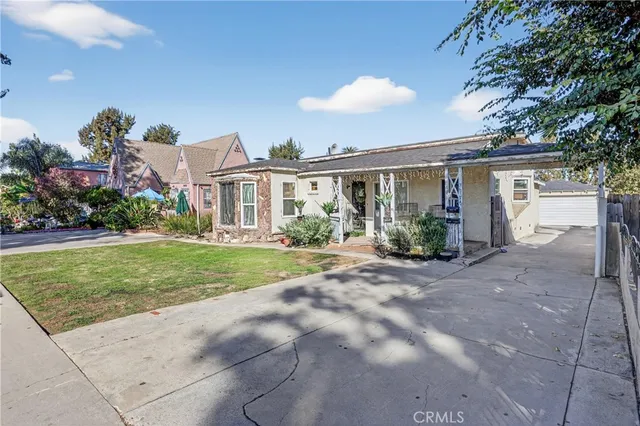 a view of house in front of a big yard with potted plants