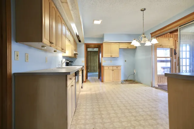 a kitchen with cabinets wooden floor and a chandelier