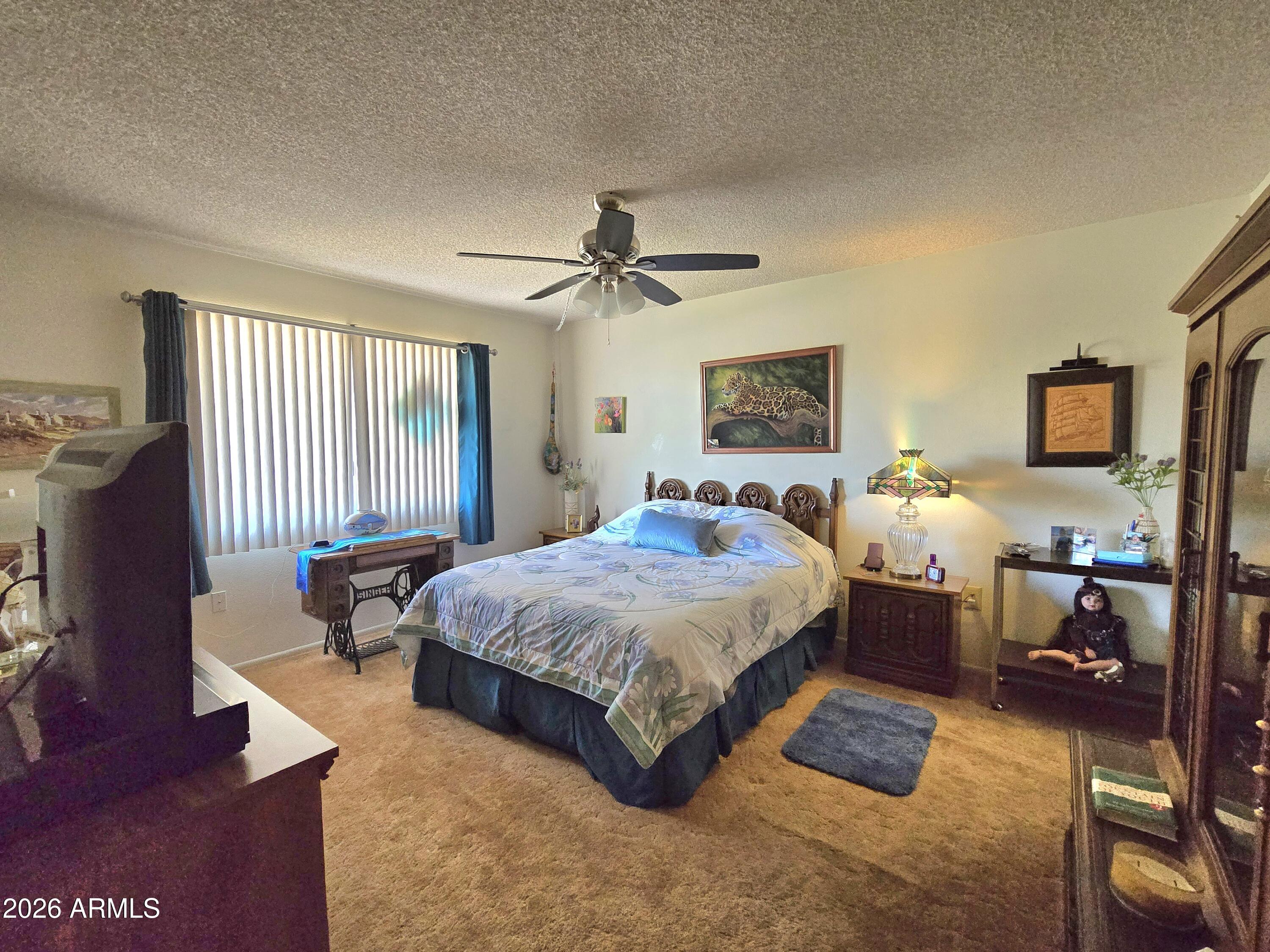 11634 North Rio Vista Drive Sun City, AZ 85351 - Photo 6 of 15 a spacious bedroom with a bed a couch and a dresser with wooden floor