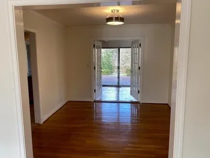 an empty room with wooden floor chandelier fan and windows