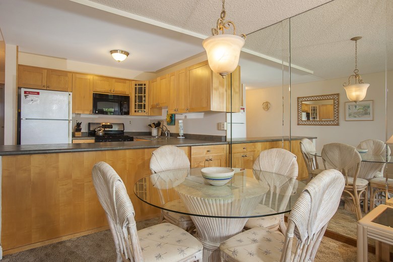 2531 South Kihei Road, Unit C512 Kihei, HI 96753 - Photo 7 of 27 a kitchen with stainless steel appliances granite countertop a sink a microwave a dining table and chairs with wooden floor