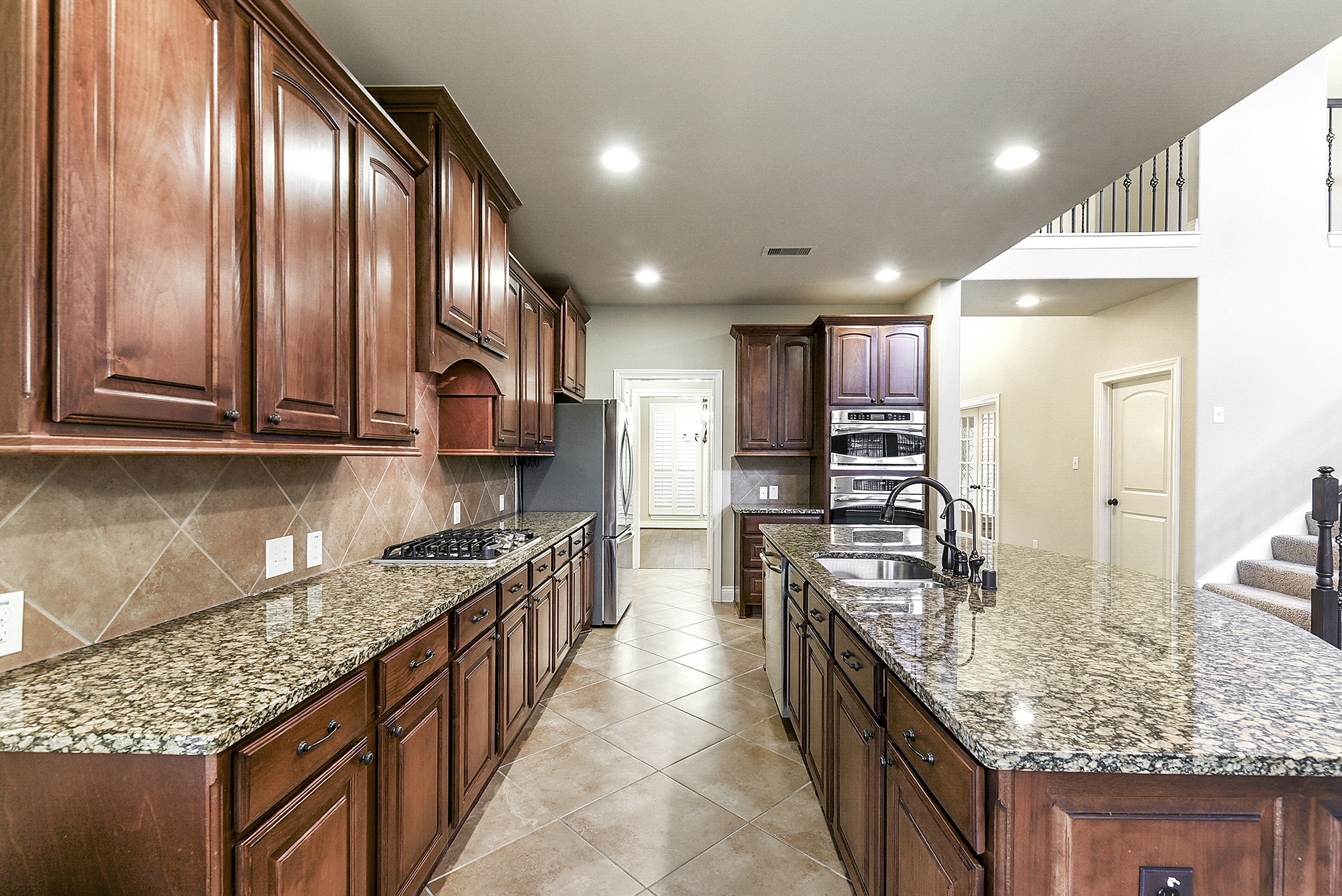 29023 Powder Ridge Drive Katy, TX 77494 - Photo 19 of 50 The kitchen offers three convenient entry points from the dining room, breakfast room, and living area, creating an open and connected flow throughout the main living spaces. Rich wood cabinetry with stylish hardware enhances both functionality and elegance, complemented by expansive granite countertops. The kitchen features a gas range, wall oven, and built-in microwave. A large walk-in pantry is conveniently located along the pass-through to the dining room, dedicated coffee nook next to the refrigerator.