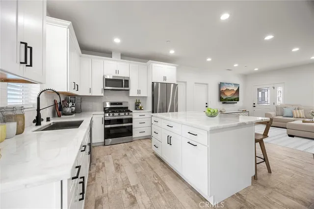 a kitchen with stainless steel appliances kitchen island granite countertop a stove top oven a sink a refrigerator and white cabinets