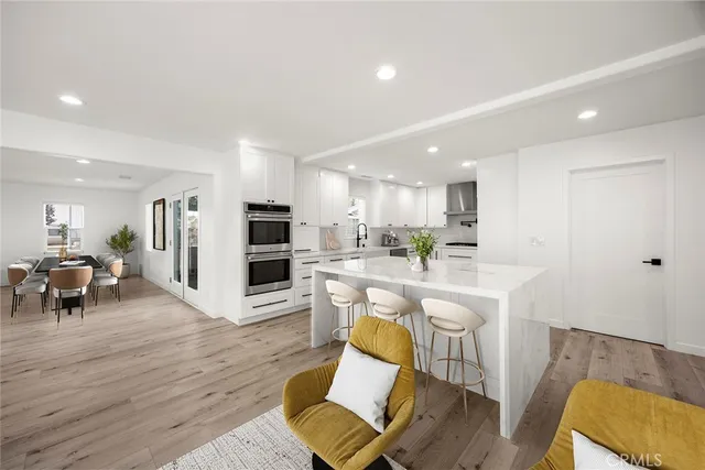 a living room with stainless steel appliances furniture and a wooden floor
