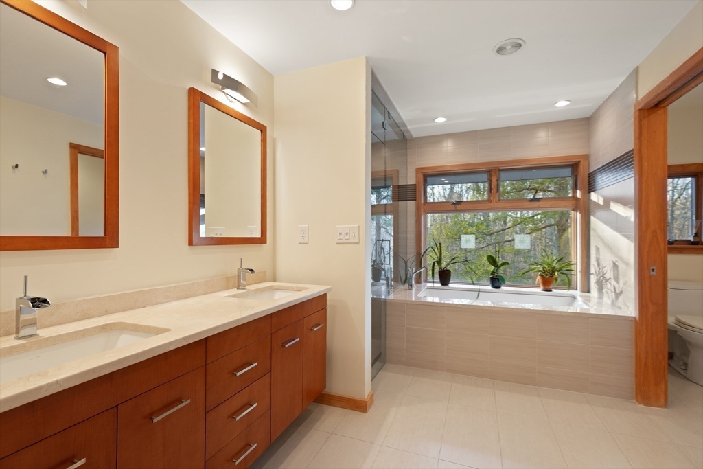 175 Mountain Street Sharon, MA 02067 - Photo 15 of 28 a bathroom with a double vanity sink a large mirror a bathtub and next to a window