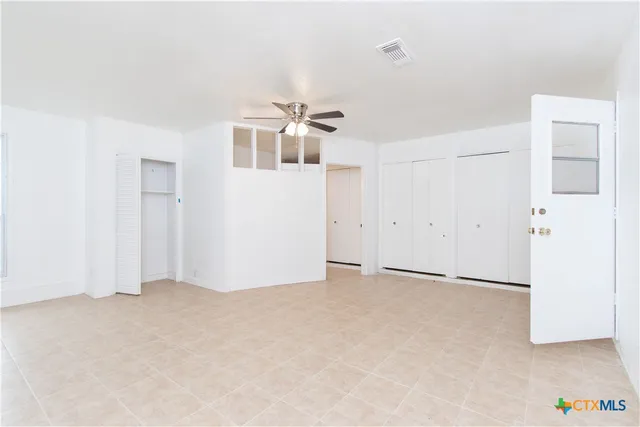 an empty room with a ceiling fan and windows
