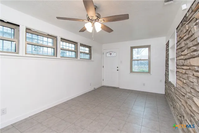 an empty room with windows and fan