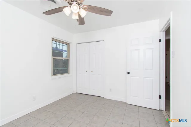 an empty room with windows and fan