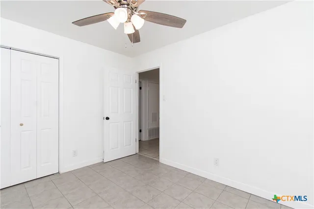 an empty room with a chandelier fan and closet
