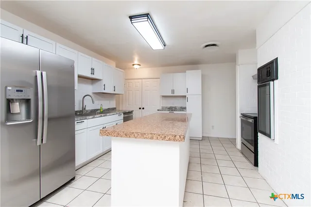 a kitchen with stainless steel appliances granite countertop a refrigerator and a sink
