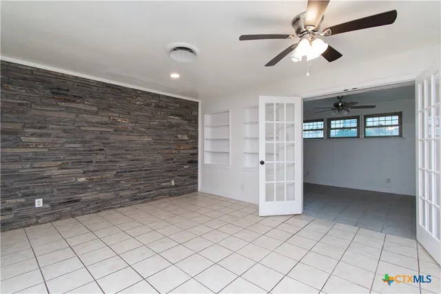 en empty room with a ceiling fan and window