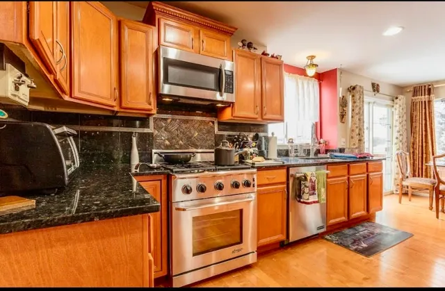 a kitchen with stainless steel appliances granite countertop a stove a sink and a microwave
