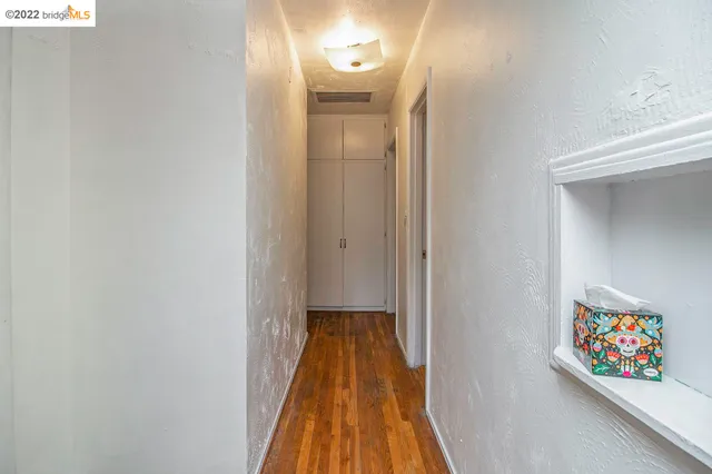 a view of a hallway with wooden floor and a bathroom