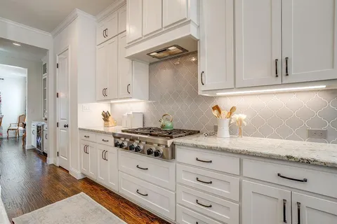 a kitchen with granite countertop white cabinets and white appliances