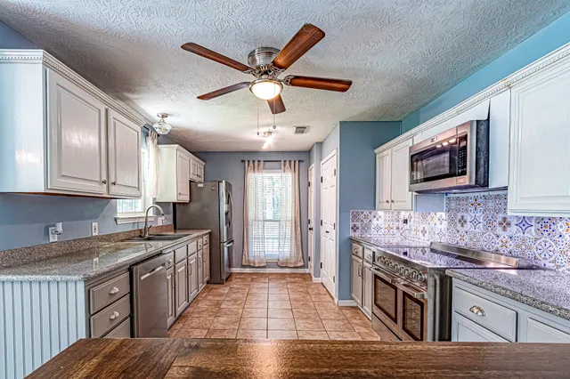 a kitchen with stainless steel appliances granite countertop a stove top oven a sink a counter top space and cabinets