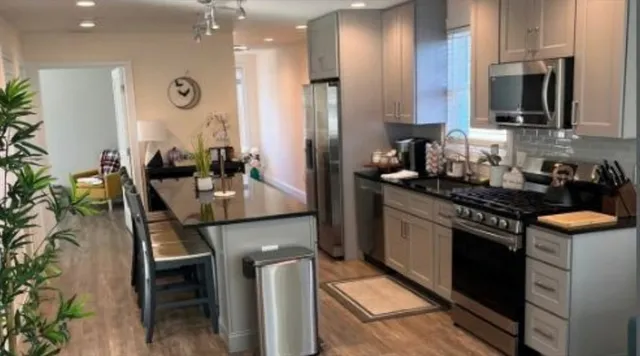 a kitchen with stainless steel appliances granite countertop a stove a sink a refrigerator and a microwave