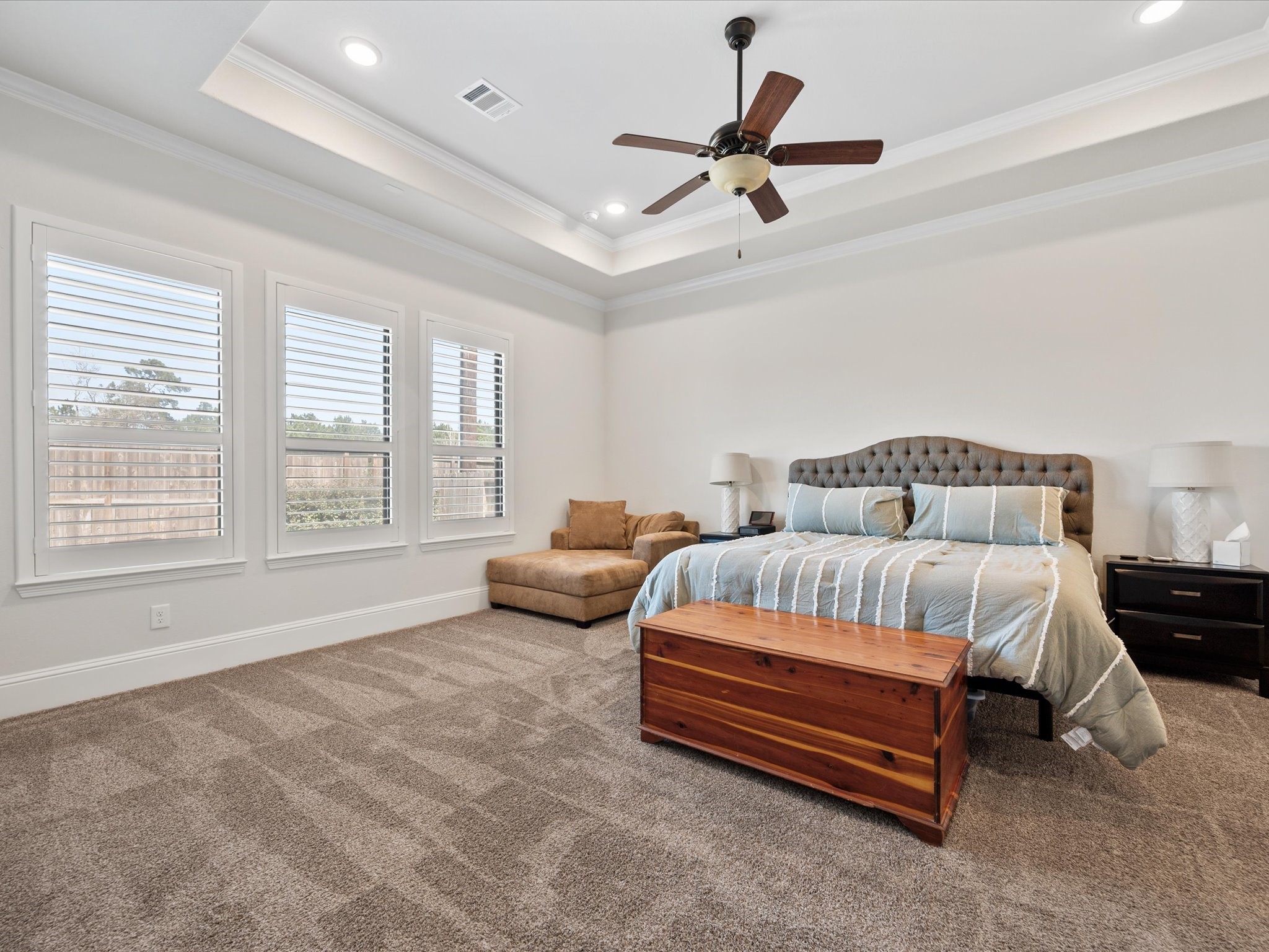 605 Ashbrook Ridge Lane Pinehurst, TX 77362 - Photo 21 of 46 The expansive primary bedroom features a tray ceiling and large windows with plantation-style shutters, creating a serene retreat.