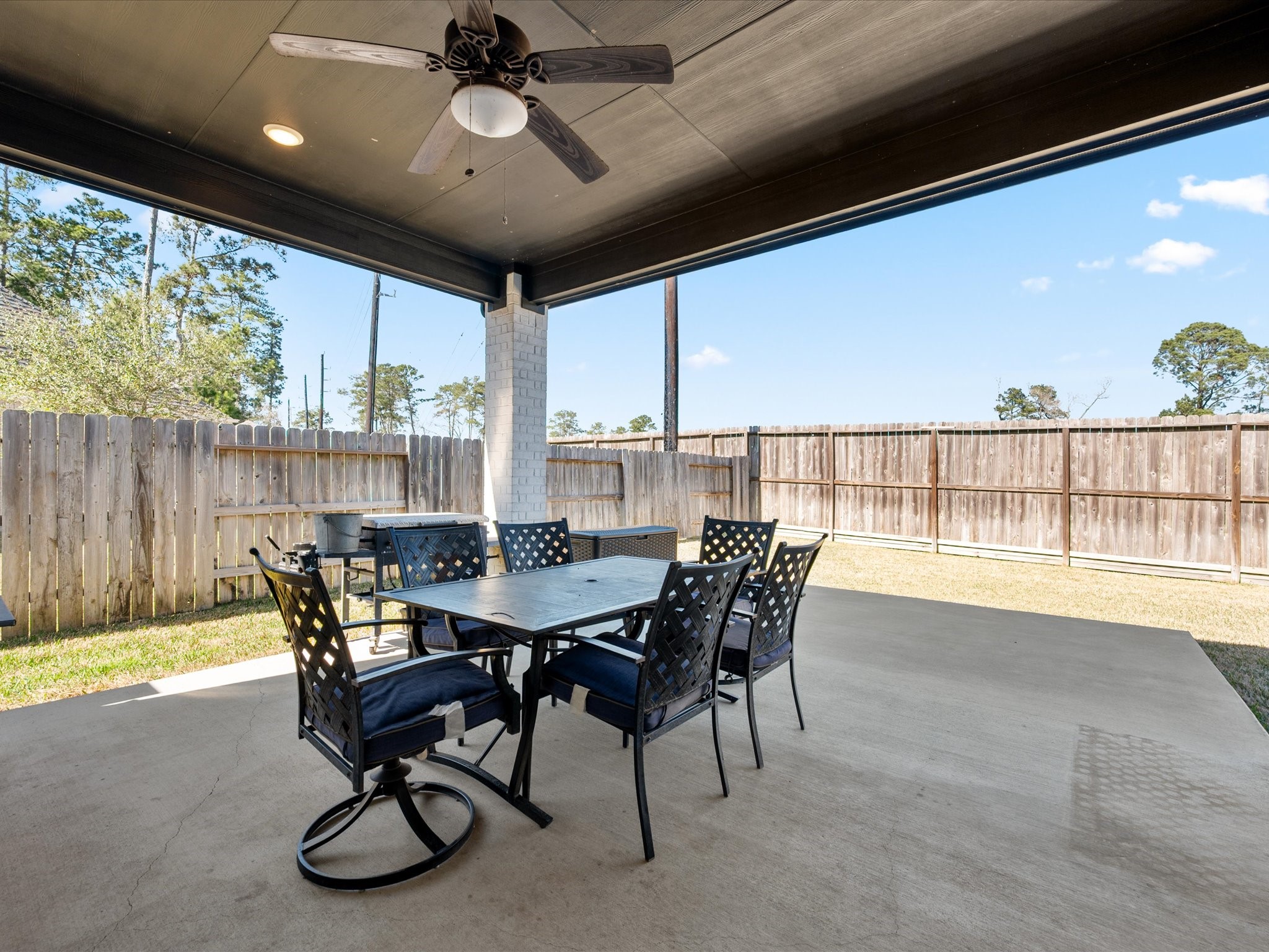 605 Ashbrook Ridge Lane Pinehurst, TX 77362 - Photo 34 of 46 Step outside to a large covered patio with a ceiling fan overlooking the expansive backyard — no back neighbors and peaceful green space beyond.