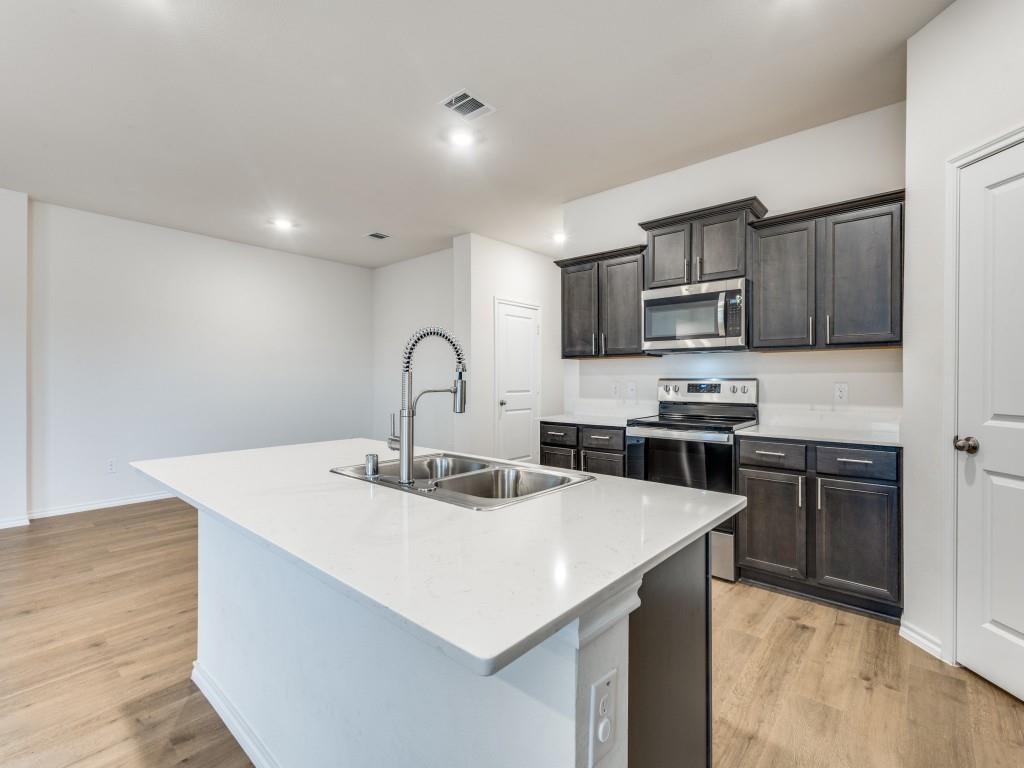 829 Primrose Lane Pilot Point, TX 76258 - Photo 16 of 37 a kitchen with kitchen island a sink appliances and cabinets