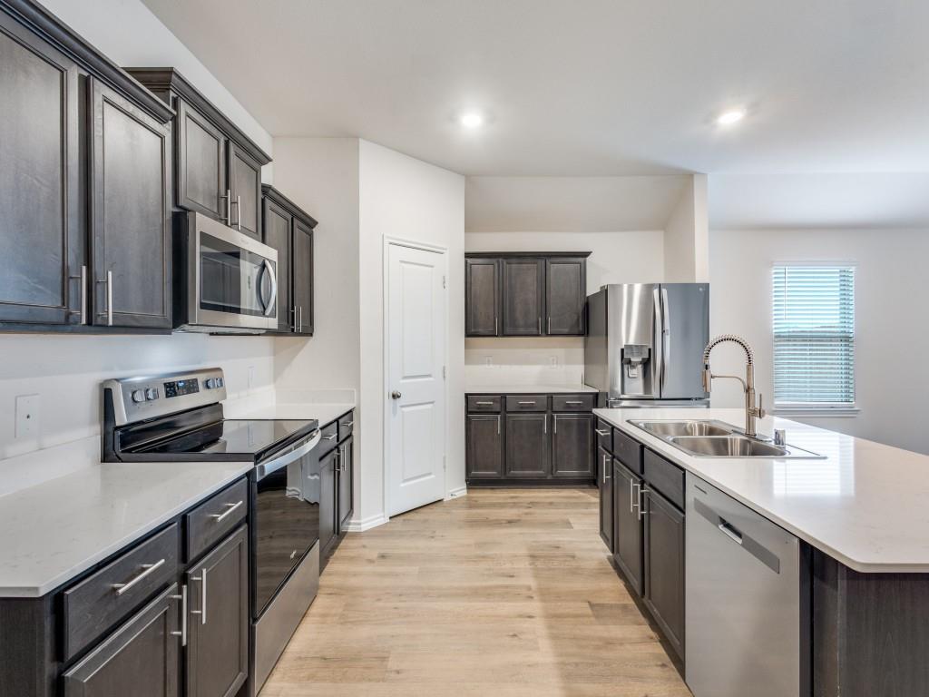 829 Primrose Lane Pilot Point, TX 76258 - Photo 17 of 37 a kitchen with stainless steel appliances granite countertop a sink stove microwave and cabinets