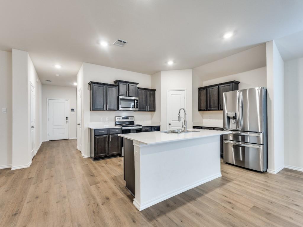 829 Primrose Lane Pilot Point, TX 76258 - Photo 18 of 37 a kitchen with kitchen island a sink cabinets and stainless steel appliances