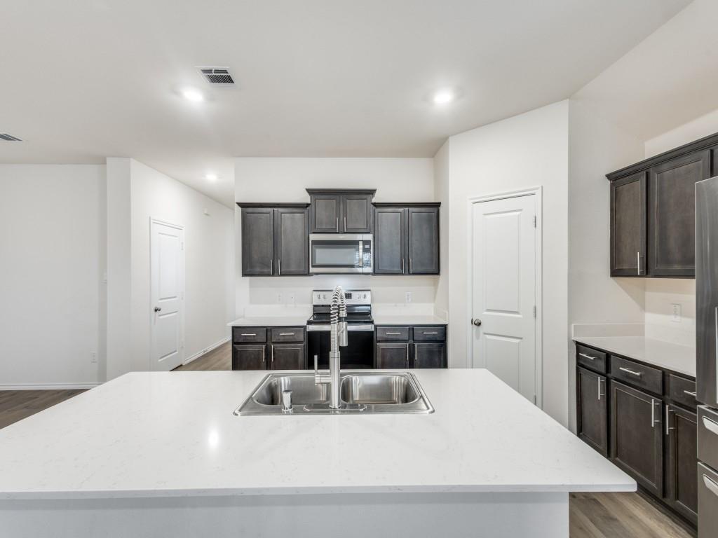 829 Primrose Lane Pilot Point, TX 76258 - Photo 19 of 37 a kitchen with stainless steel appliances kitchen island granite countertop a sink and cabinets