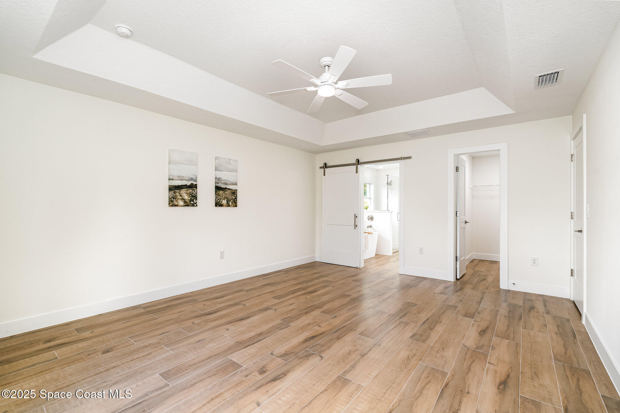 6003 Gilson Avenue Cocoa, FL 32927 - Photo 15 of 27 a view of an empty room with wooden floor and a ceiling fan