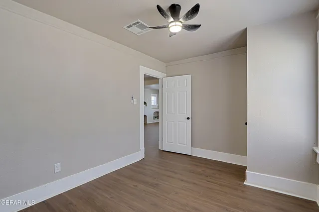 a view of empty room with wooden floor and fan