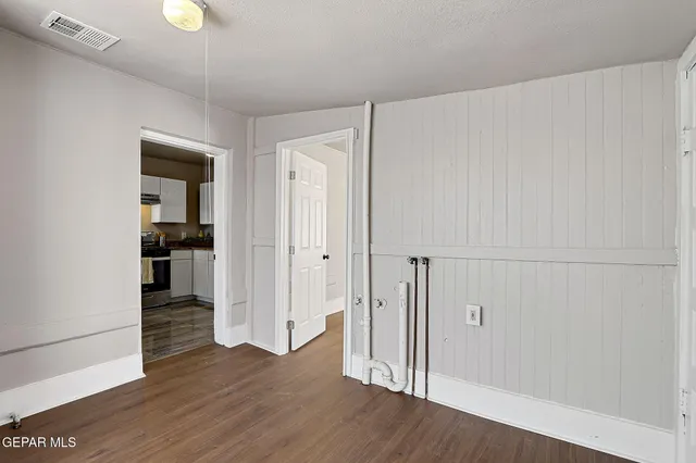a view of an empty room with wooden floor and closet