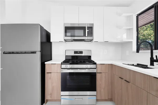a kitchen with stainless steel appliances a stove a microwave and a sink