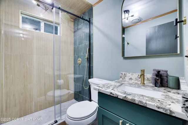 a bathroom with a granite countertop sink a toilet a mirror and shower