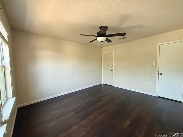 an empty room with wooden floor and chandelier fan