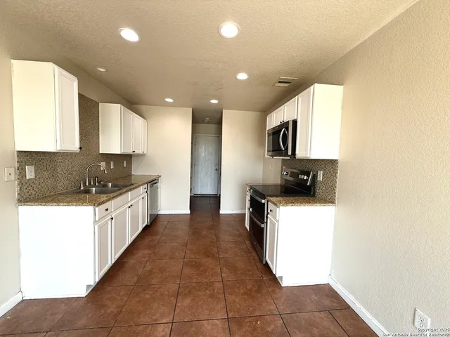 a large kitchen with a large counter top a sink a stove a microwave and a refrigerator