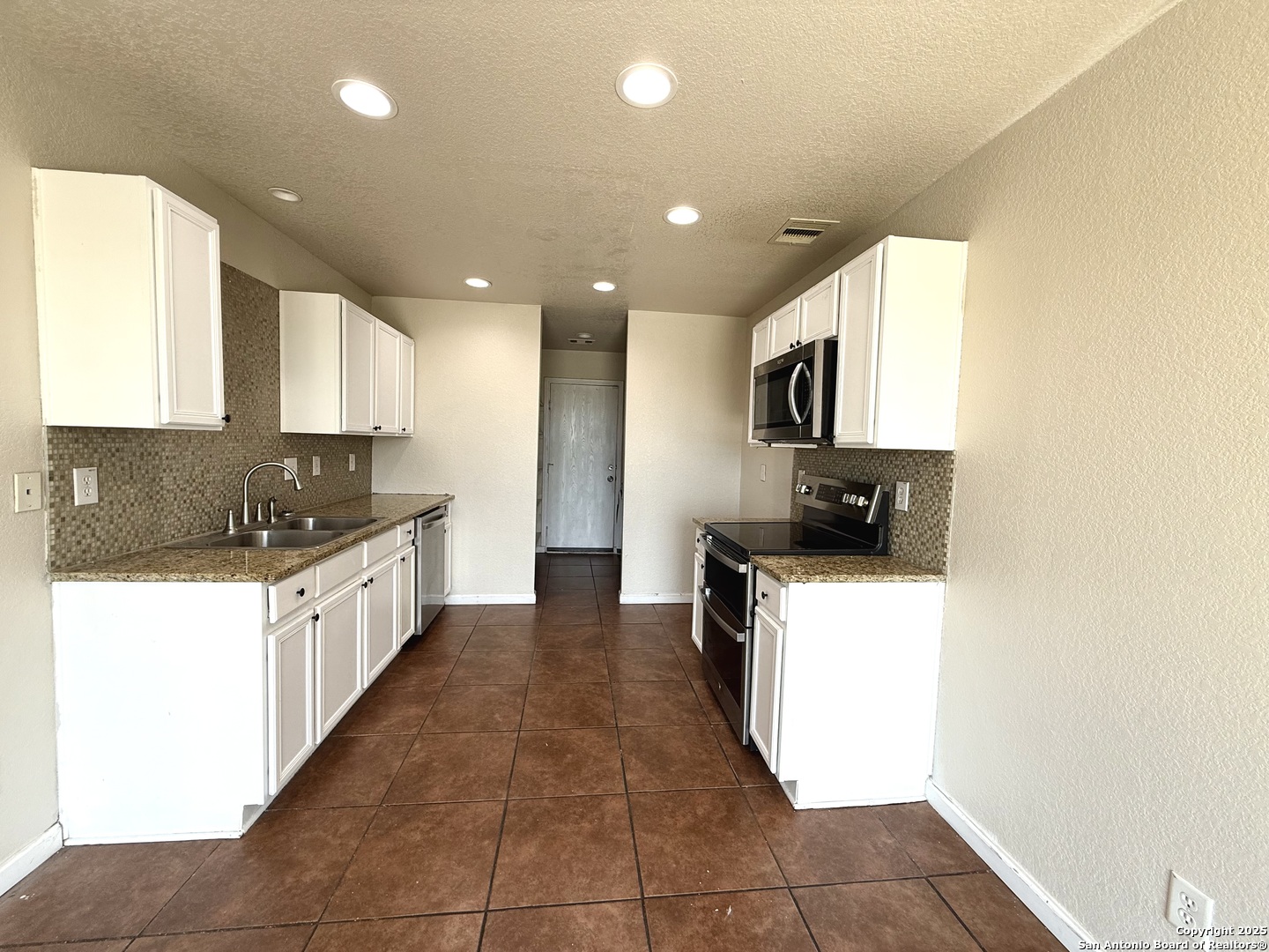 6118 Kensinger Pass Converse, TX 78109 - Photo 3 of 30 a large kitchen with a large counter top a sink a stove a microwave and a refrigerator