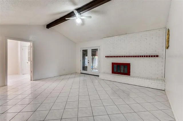 a view of an empty room with a fireplace and a chandelier fan