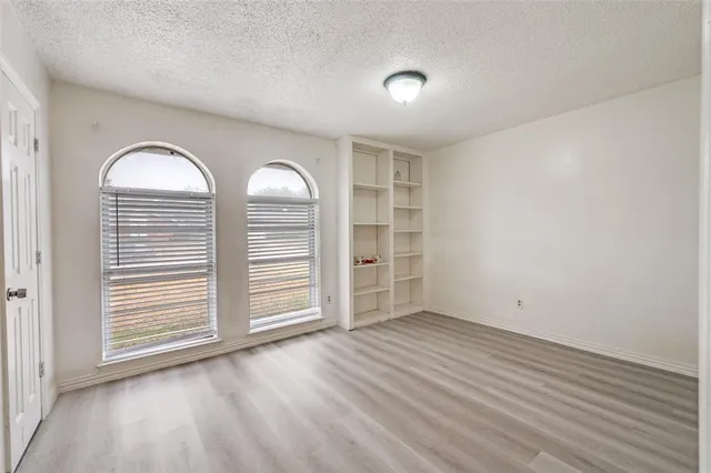 an empty room with wooden floor cabinet and windows