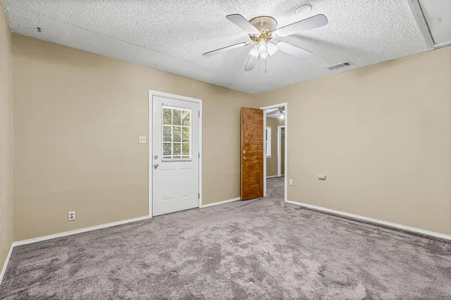 an empty room with windows and fan