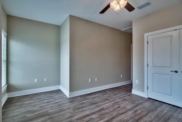 an empty room with wooden floor and ceiling fan