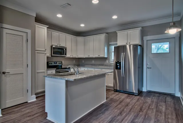 a kitchen with a refrigerator a stove top oven and wooden floor