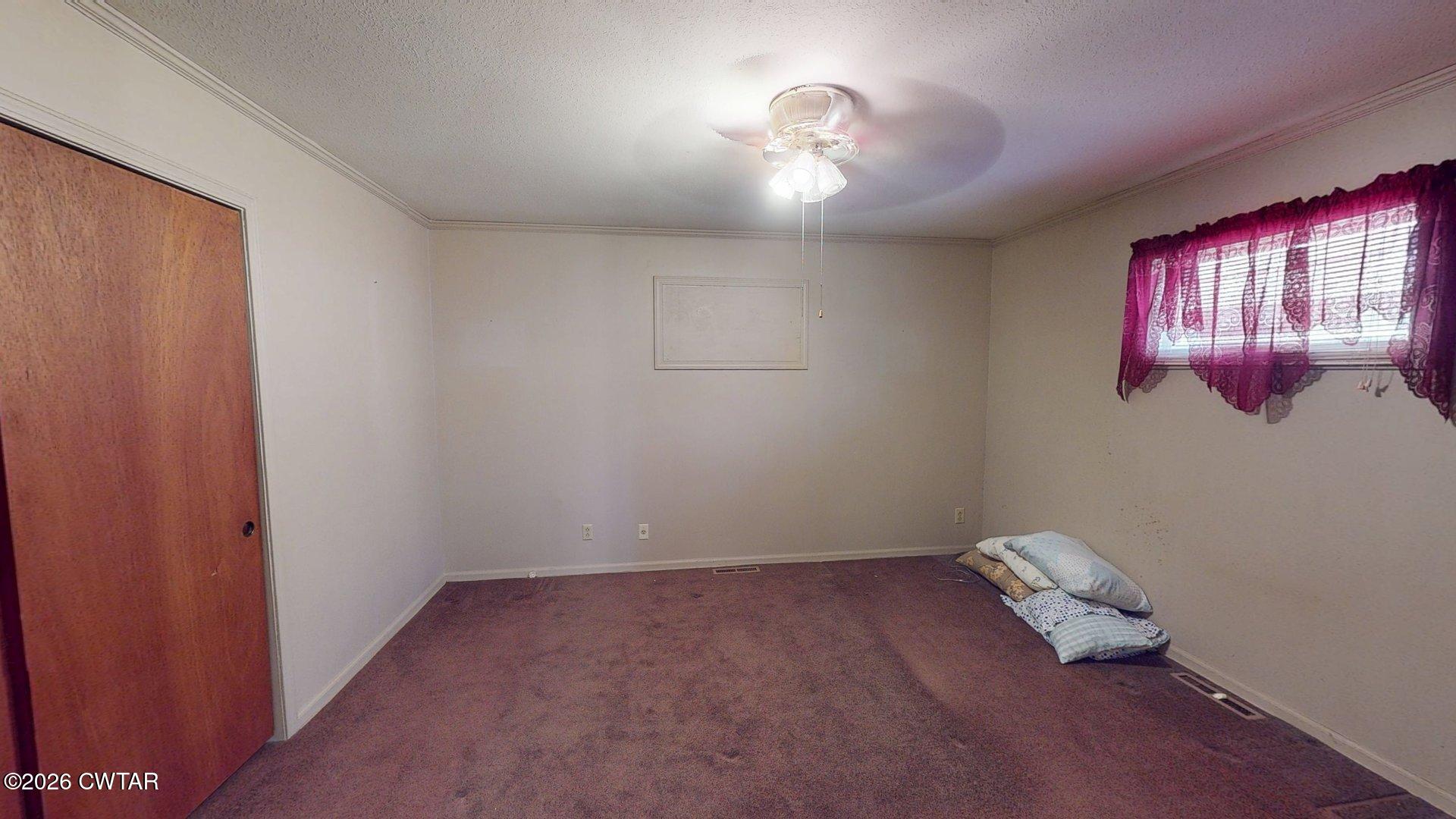 228 Lake Street Ridgely, TN 38080 - Photo 7 of 18 an empty room with a chandelier fan and wooden floor