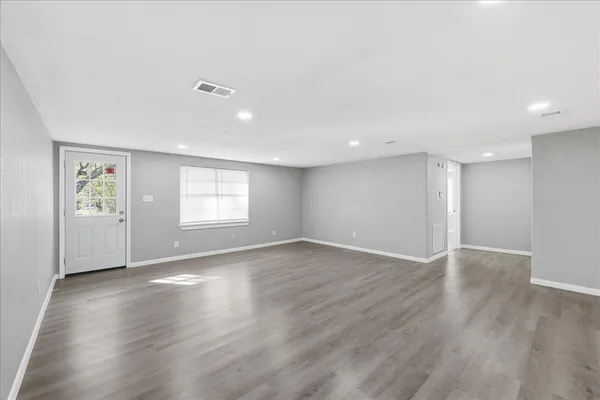 an empty room with wooden floor and windows