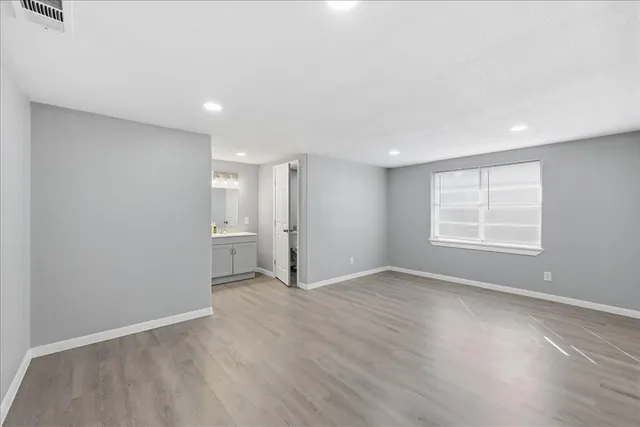 a view of an empty room with a window and wooden floor