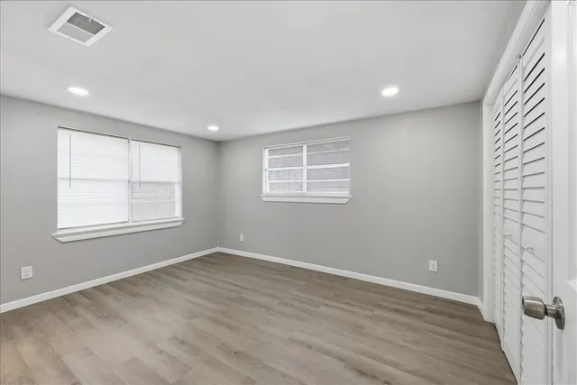 an empty room with wooden floor and windows