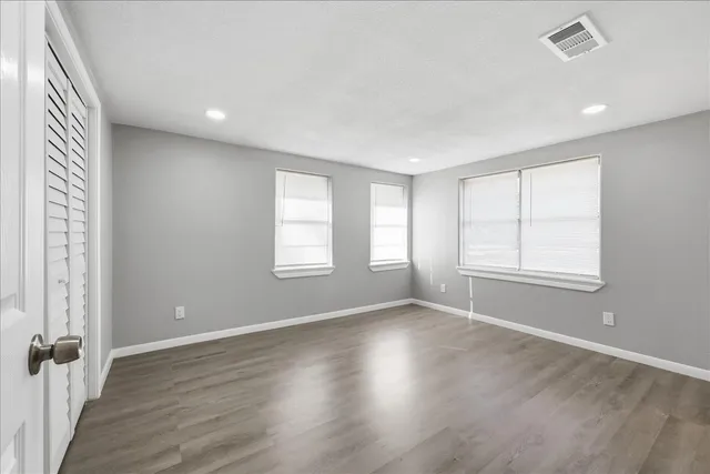 an empty room with wooden floor and windows