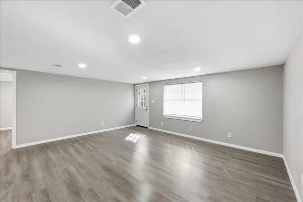an empty room with wooden floor and windows