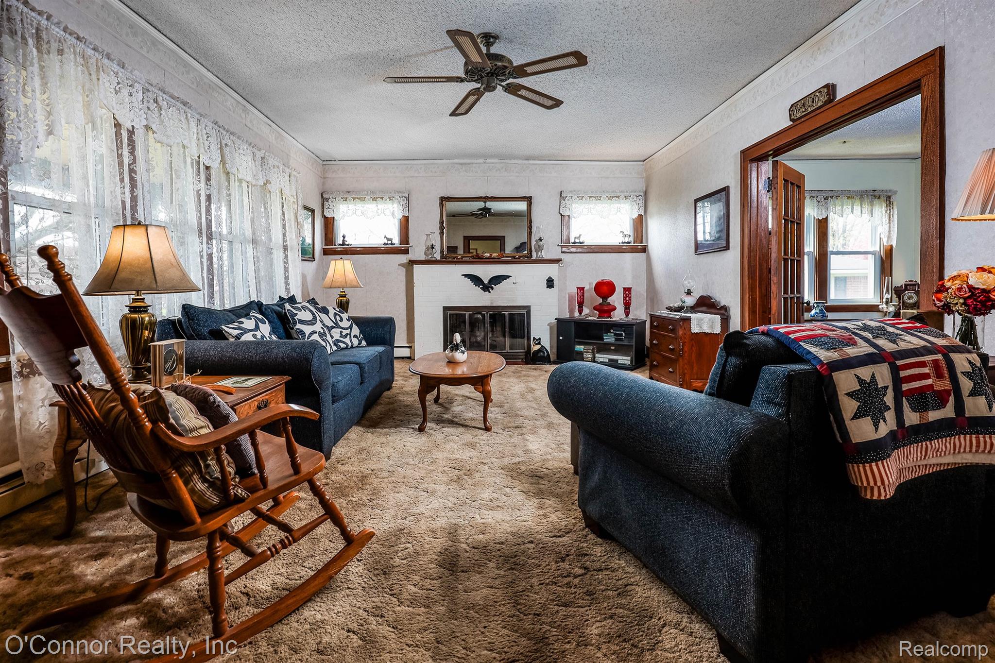 3323 Kinney Road Emmett, MI 48022 - Photo 4 of 29 Living area featuring a textured ceiling, a ceiling fan, and a built-in fireplace with a mantel
