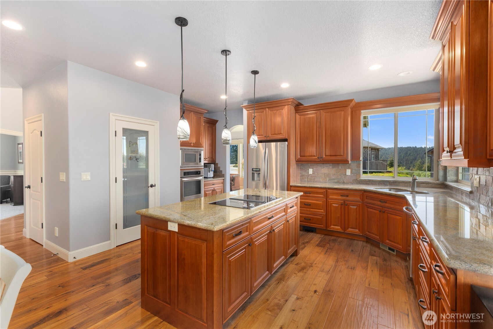 3015 Lighthouse Keepers Road Ilwaco, WA 98624 - Photo 11 of 40 a large kitchen with stainless steel appliances granite countertop a stove a sink dishwasher a refrigerator and wooden cabinets with wooden floor