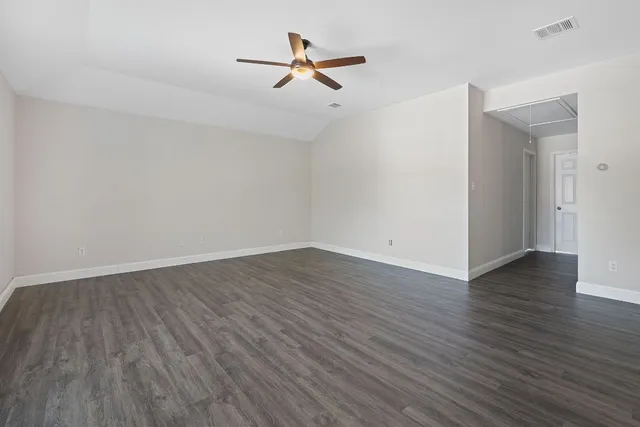 an empty room with wooden floor a ceiling fan and a window