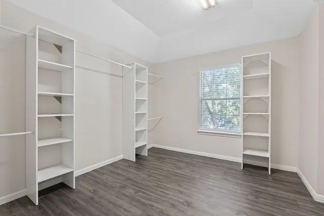 an empty room with wooden floor closet and windows
