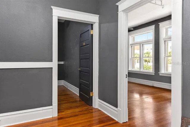 a view of a hallway with wooden floor and a room